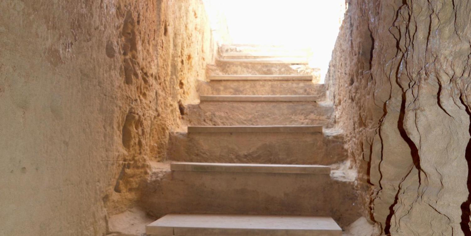 Steintreppe führt nach oben zu einem hell erleuchteten Ausgang.