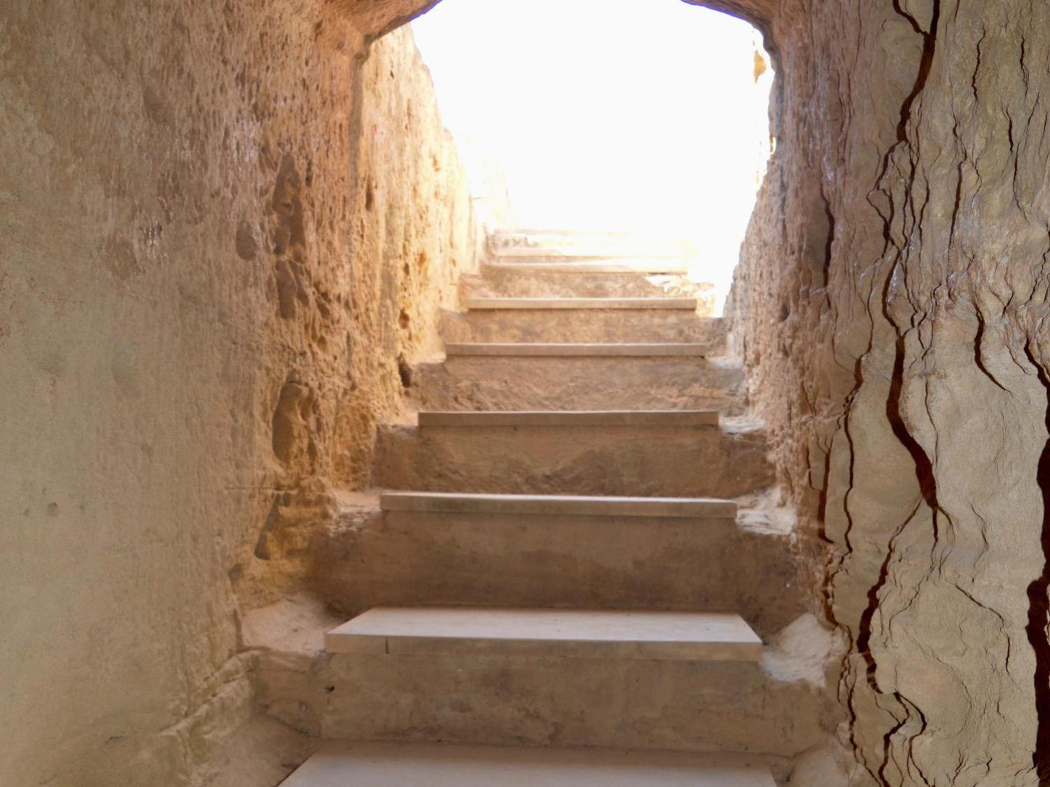 Steintreppe führt nach oben zu einem hell erleuchteten Ausgang.